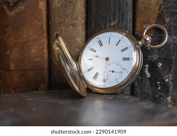 Gold pocket watch "Pavel Bure" on a gold pendant. Royal Russia. pocket watch on a dark background with books. Image of an antique gold pocket watch on an old antique book.
