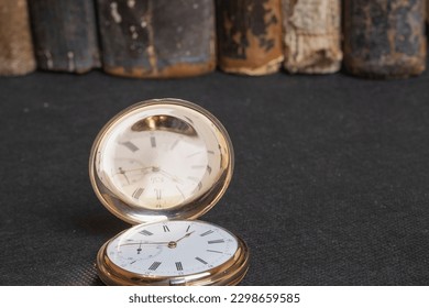 Gold pocket watch "Pavel Bure" on a gold pendant. Royal Russia. pocket watch on a dark background with books. Image of an antique gold pocket watch on an old antique book.
