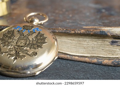 Gold pocket watch "Pavel Bure" on a gold pendant. Royal Russia. pocket watch on a dark background with books. Image of an antique gold pocket watch on an old antique book.