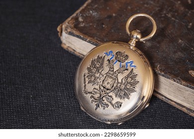 Gold pocket watch "Pavel Bure" on a gold pendant. Royal Russia. pocket watch on a dark background with books. Image of an antique gold pocket watch on an old antique book.