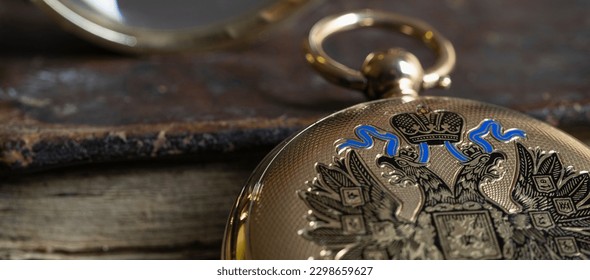 Gold pocket watch "Pavel Bure" on a gold pendant. Royal Russia. pocket watch on a dark background with books. Image of an antique gold pocket watch on an old antique book.