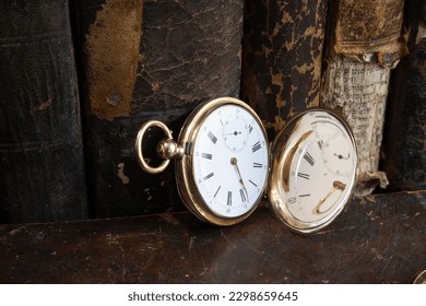 Gold pocket watch "Pavel Bure" on a gold pendant. Royal Russia. pocket watch on a dark background with books. Image of an antique gold pocket watch on an old antique book.