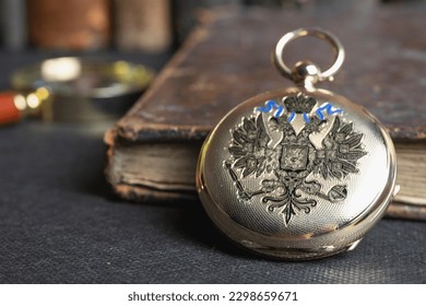 Gold pocket watch "Pavel Bure" on a gold pendant. Royal Russia. pocket watch on a dark background with books. Image of an antique gold pocket watch on an old antique book.
