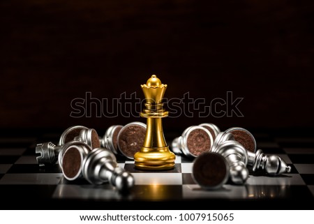 gold queen chess surrounded by a number of fallen silver chess pieces , business strategy concept