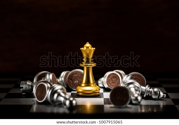 gold queen chess surrounded by\
a number of fallen silver chess pieces , business strategy\
concept