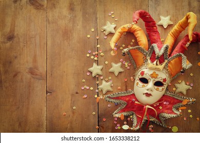 Gold And Red Elegant Traditional Venetian Jester Mask Over Old Wooden Background