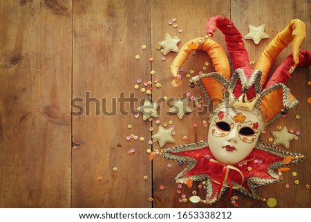 Gold and red elegant traditional Venetian jester mask over old wooden background