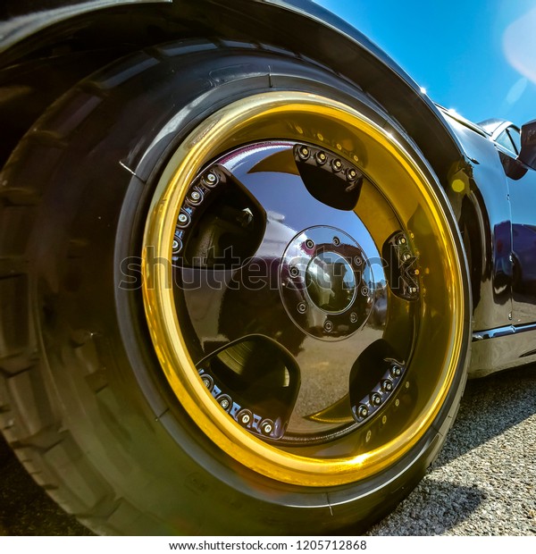 Gold rim and\
black spokes on a black cars\
wheels