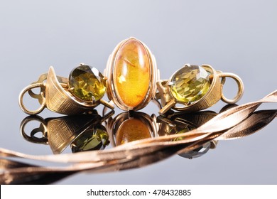 Gold ring with amber and earrings with green stones against snake skin golden chain