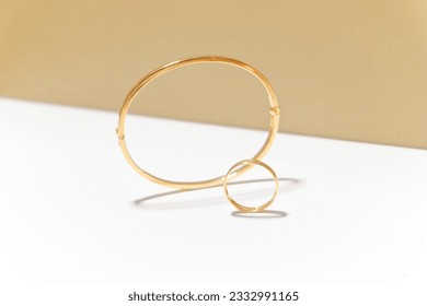 A gold ring and gold bracelet of cartier captured on the white and brown background