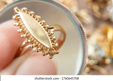 gold ring closeup, jewelry scrap of gold and silver and money, pawnshop concept jeweler looking at jewelry through magnifying glass, jewerly inspect and verify