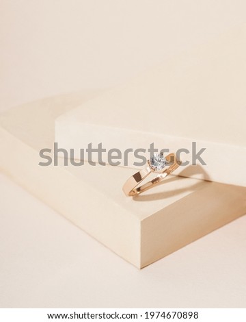 Gold ring with diamond on beige  background with shadows and geometric props. Still life and creative photo