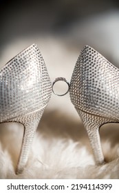 A Gold Ring Hangs Between Wedding Shoes.