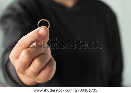 Gold Ring Held Between Fingers in Soft Lighting