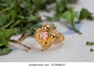 Gold Ring With Pink Stone On Green And White Background