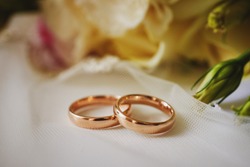 Gold Rings And A Beautiful Bridal Bouquet Of Roses On The Background. Details, Wedding Traditions. Close-up, Macro