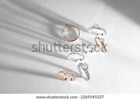 Gold rings with diamonds on white background. Still life and creative photo with shadows. Diamond stacked rings group minimal concept 