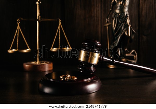 Gold rings on wooden mallet in a courtroom.\
Divorce concept