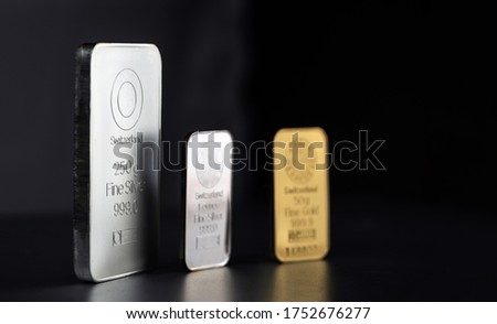 Gold and silver bars of different weights on a dark background. Selective focus.
