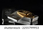 Gold and silver bars of various weights on a dark background. Selective focus.