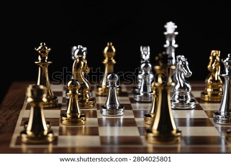 Gold and silver chess figures placed on wooden chessboard. Intellectual duel and tactical battle in business. Strategy planning, leadership and teamwork concept. Close-up metal chess pieces on board