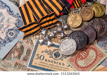 Gold and silver coins of the Russian Empire19 - 20 century in the background kopyur.Five rubles Nicholas II.Concept Russian antiques.Saint George cross of Imperial Russia.Antikvariat.