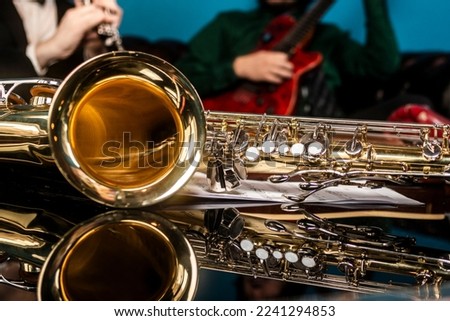 A gold and silver saxophone on a mirrored table
