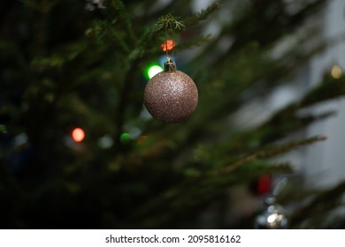 Gold Sparkly Christmas Bauble On Branch Of A Real Christmas Tree. Close Up, Shallow Depth Of Field.