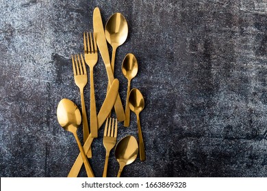 gold spoon and fork knife cutlery over grey