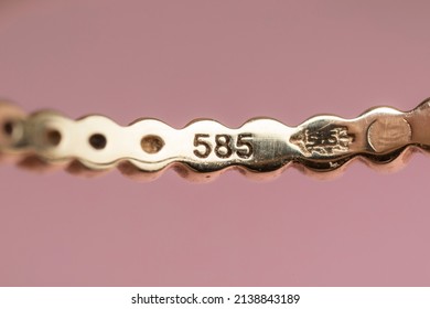 Gold stamp 585 also known as 14k  mark and a leaf icon on a real golden ring, indicating the purity of gold in the jewellery. Detail shot - Shutterstock ID 2138843189