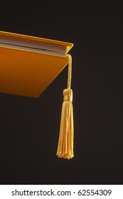 A Gold Tassel Hanging Out Of A Hard Cover Book On The Black Background Metaphor For Graduation Cap