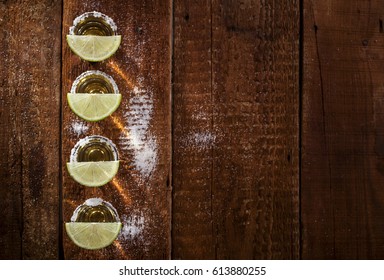 Gold Tequila Shots With Lime Fruits On Wooden Background