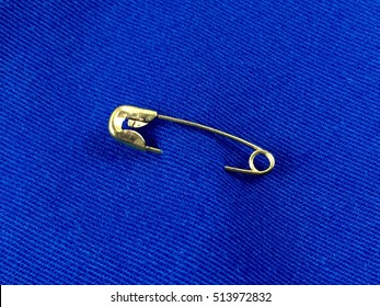 Gold Toned Safety Pin On Blue Fabric