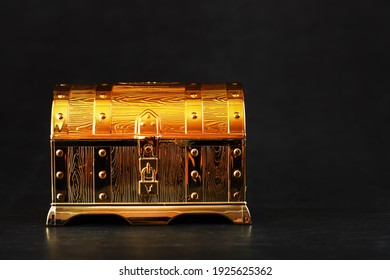 Gold Treasure Chest On A Black Textured Background. Closed Box With Money And Jewelry. Free Space