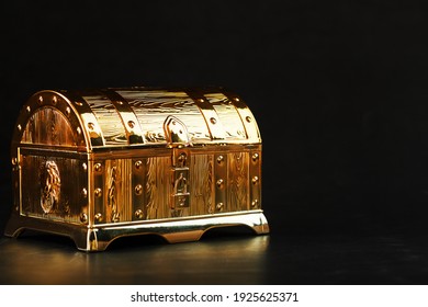 Gold Treasure Chest On A Black Textured Background. Closed Box With Money And Jewelry. Free Space