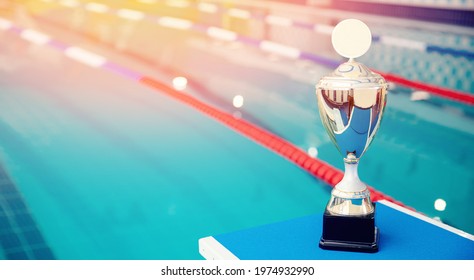 Gold trophy with blurred background of swimming pool, concept banner award swimmer.