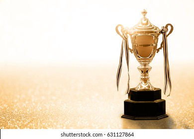 Gold Trophy competition on the abstract glitter background with copy space