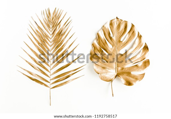 Gold tropical palm leaves Monstera\
on white background. Flat lay, top view minimal\
concept.