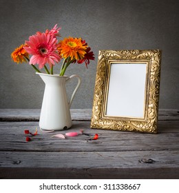 Gold Vintage Photo Frame And Flowers On Wooden Table Over Grunge Background