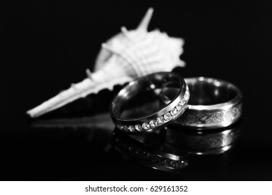 Gold wedding ring and shell on black background
