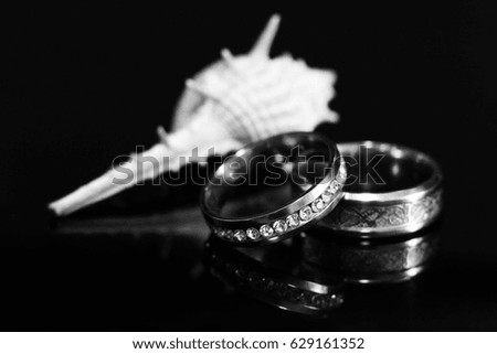 Gold wedding ring and shell on black background
