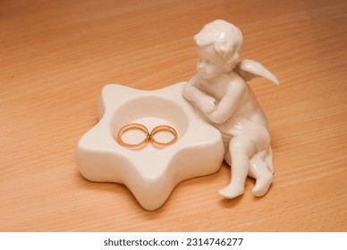 Gold wedding rings lie on a porcelain figurine of an angel