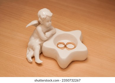Gold wedding rings lie on a porcelain figurine of an angel