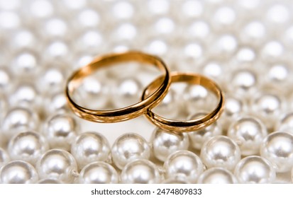 Gold wedding rings lie on a pearl necklace
 - Powered by Shutterstock