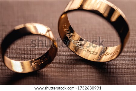 Gold wedding rings for newlyweds with an engraving inside. Close-up of rings on the table. Macro shooting of objects