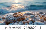 gold wedding rings on stone on the beach at sunshine