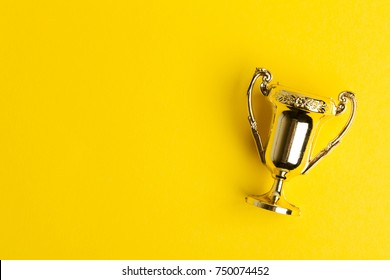 Gold winners achievement trophy on a yellow background