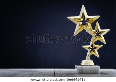 Gold winners award with three stars to be awarded to the first place in a competition or championship standing on a pedestal against a blue background with copy space