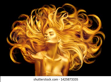 Gold Woman. Beauty fashion model girl with Golden make up, and Long hair pointing hand on black background. Gold glowing skin and fluttering hair. Metallic, glance Fashion art portrait, Hairstyle