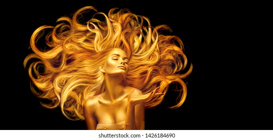 Gold Woman. Beauty fashion model girl with Golden make up, and Long hair pointing hand on black background. Gold glowing skin and fluttering hair. Metallic, glance Fashion art portrait, Hairstyle